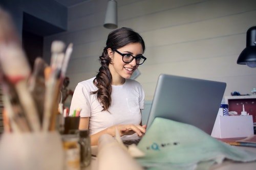 Pintora mujer frente a computadora trabajando en un escritorio.
