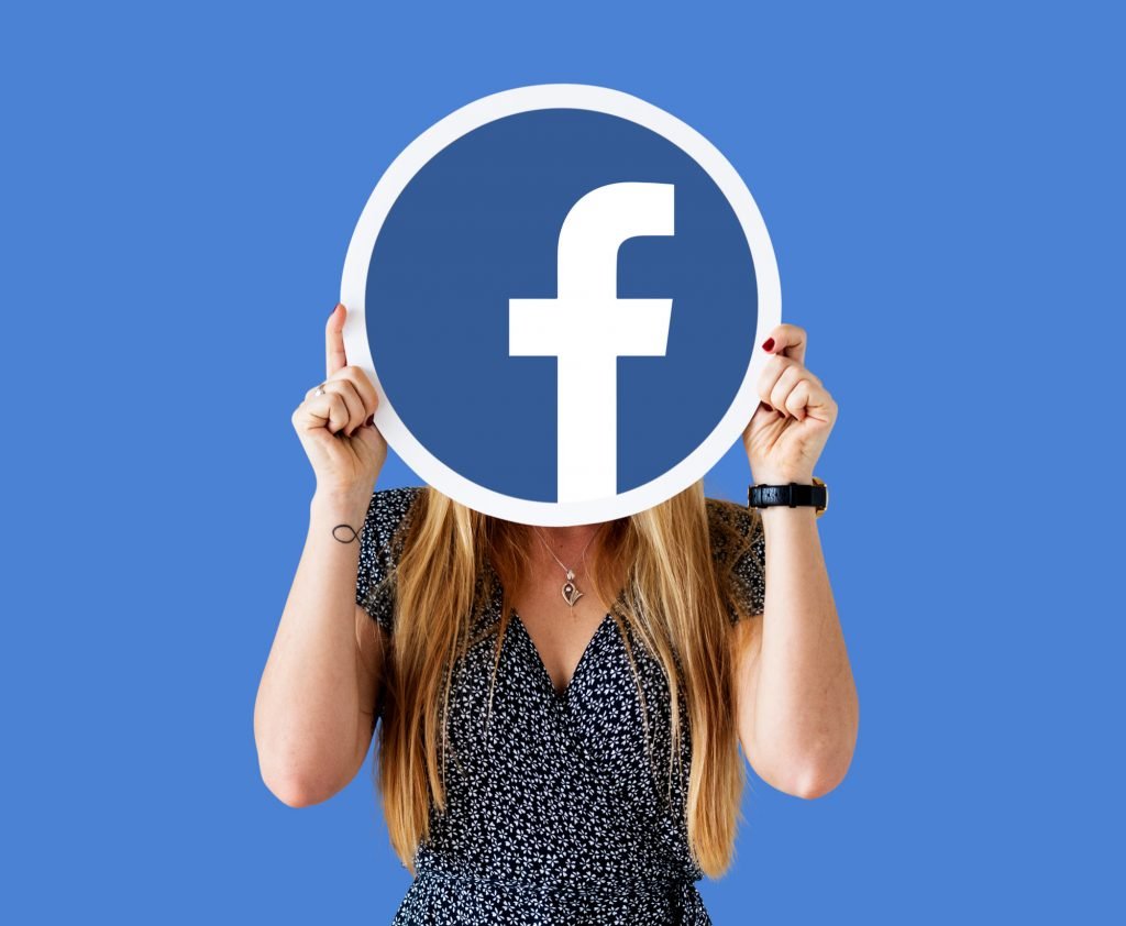 Mujer sosteniendo logotipo de Facebook a altura de su cara. 5 consejos de qué hacer en redes sociales y otros medios digitales